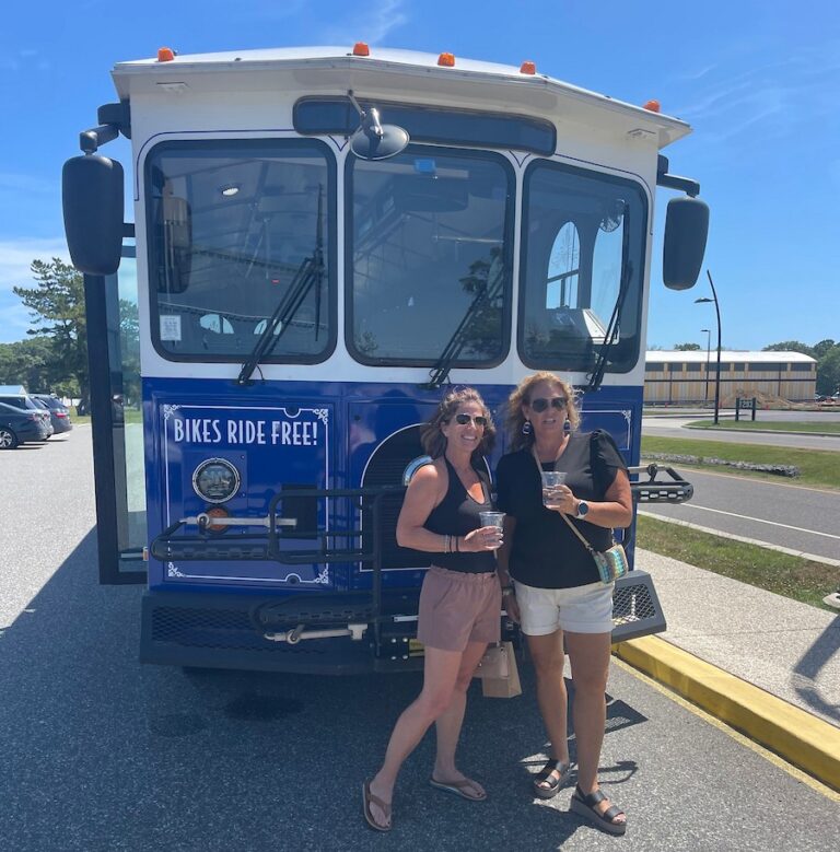 Two ladies pose in front of the Ferry shuttle during their brewery excursion