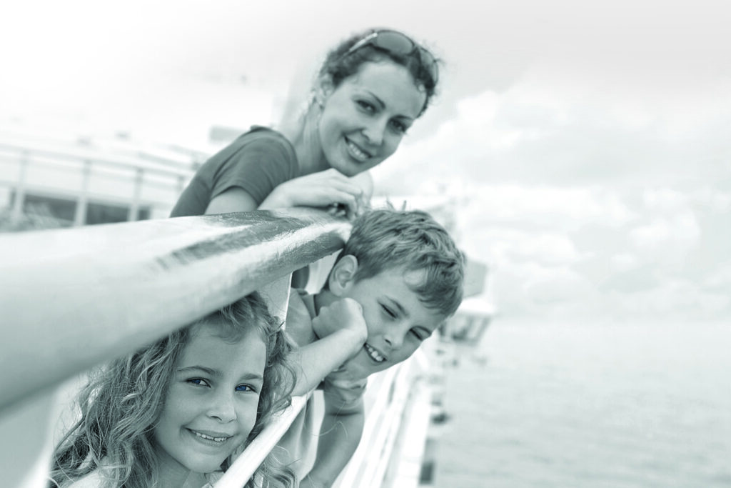 A family of 3 smiles for a photo, leaning on the Ferry deck